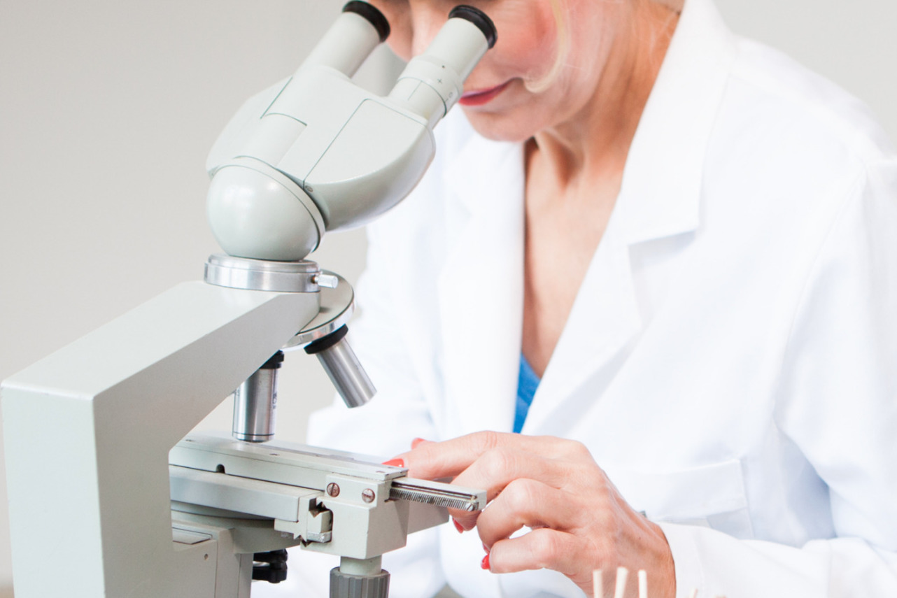 Technician examining a specimen through a microscope